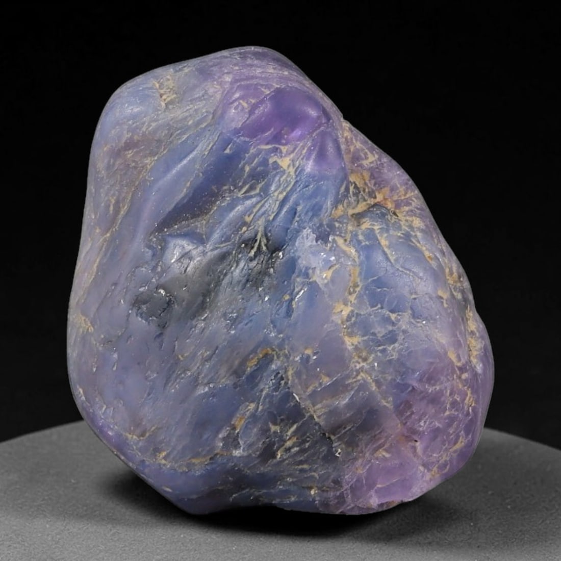 27.39ct Natural Unheated Sri Lankan Purplish Blue Sapphire Rough, 79FC: This natural corundum rough is an unheated purplish blue sapphire sourced from Sri Lankan alluvial gem deposits, featuring an irregular natural native form with residual pale yellow-brown mineral matr