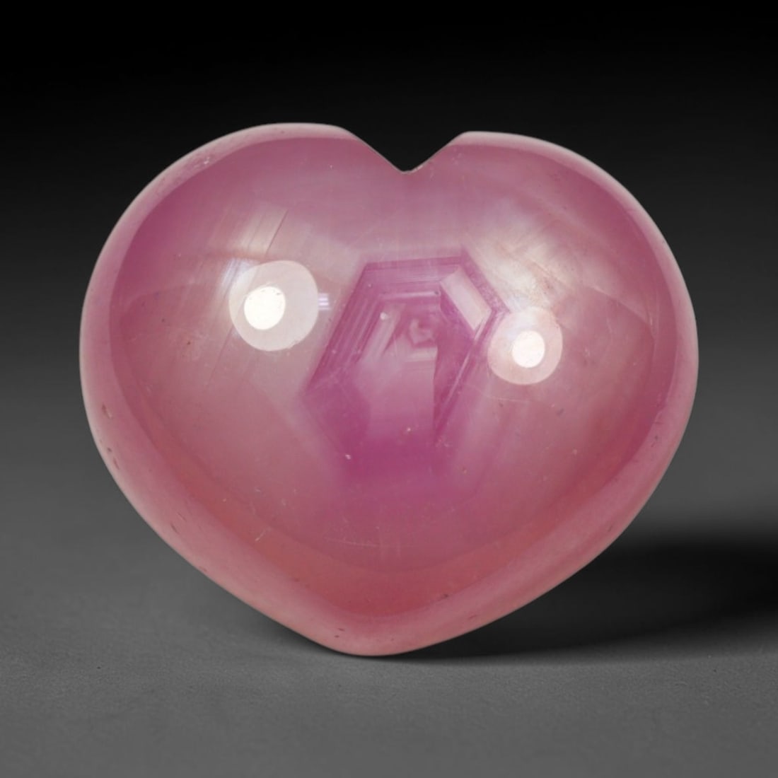 14.49ct Natural Mozambique Hot Pink Ruby Loose Gemstone, 91BP: This heart shaped Mozambique ruby cabochon measures 14.1x11.9x7.3mm, showcasing a vivid saturated hot pink body paired with stunning natural hexagonal crystal growth banding that forms a distinct geom