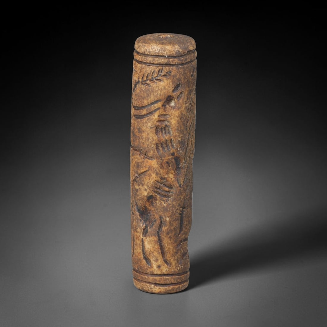 Ancient Mesopotamian Stone Cylinder Seal (c.2300-539 BCE), 69EF: This carved pale weathered stone cylinder seal originates from Ancient Mesopotamia. The cylindrical body features continuous incised imagery encircling the surface, framed by simple horizontal border 