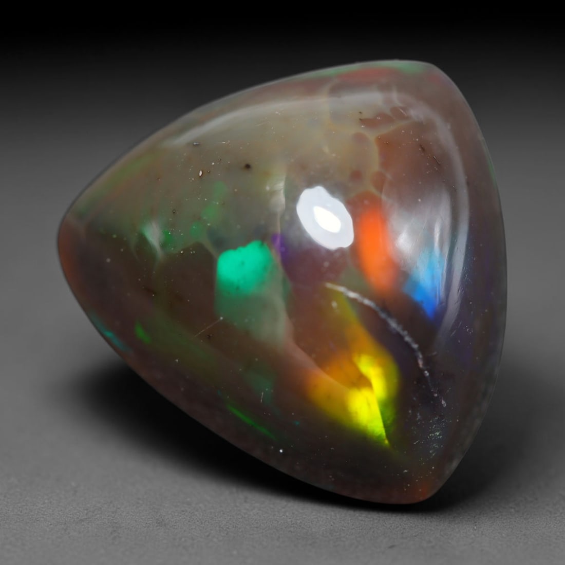 7.81ct Natural Ethiopian Welo Black Smoked Opal Cabochon Loose Gemstone, 63BY: This fully polished Ethiopian Welo opal features a dark smoked base with vivid, sweeping play-of-color shifting across its glossy dome surface, measured at 14x9mm. The black smoke treatment deepens th