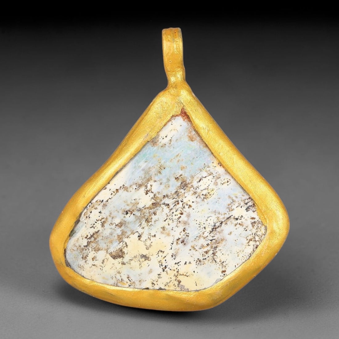 Ancient Roman Glass Slag in Modern Gilt-Edge Pendant, 56FY: This contemporary pendant is crafted from ancient Roman glass slag, featuring a fragmented, iridescent glass surface with weathered patina. The irregular form is bordered by a subtle gilt frame, added