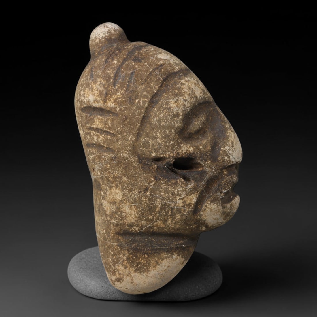 Ancient Medieval Near Eastern Tribal Hand Carved Stone Maskette Amulet, 48AC: Medium sized antique portable sacred talisman hand fashioned from natural sedimentary stone, measuring 6.5cm x 3.5cm, originating from Medieval Near Eastern tribal cultural traditions. Hand-worked sto