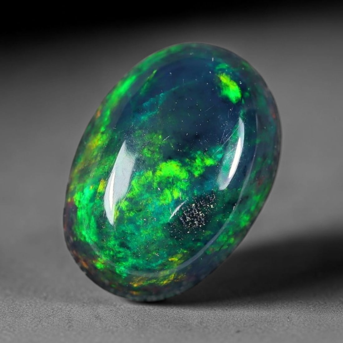 2.07ct Natural Ethiopian Welo Black Smoked Opal Cabochon Loose Gemstone, 3FX: This fully polished Ethiopian Welo opal features a dark smoked base with vivid, sweeping play-of-color shifting across its glossy dome surface, measured at 10x7x5mm. The black smoke treatment deepens 