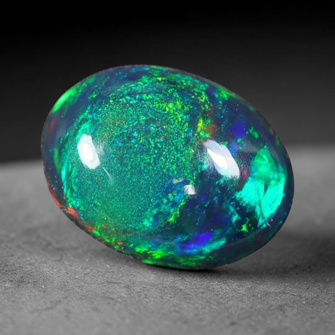 2.06ct Natural Ethiopian Welo Black Smoked Opal Cabochon Loose Gemstone, 56FX: This fully polished Ethiopian Welo opal features a dark smoked base with vivid, sweeping play-of-color shifting across its glossy dome surface, measured at 11x8x4mm. The black smoke treatment deepens 