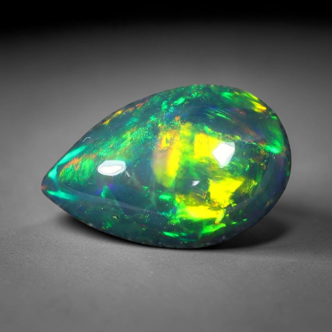1.91ct Natural Ethiopian Welo Black Smoked Opal Cabochon Loose Gemstone, 69FX: This fully polished Ethiopian Welo opal features a dark smoked base with vivid, sweeping play-of-color shifting across its glossy dome surface, measured at 11x7x5mm. The black smoke treatment deepens 