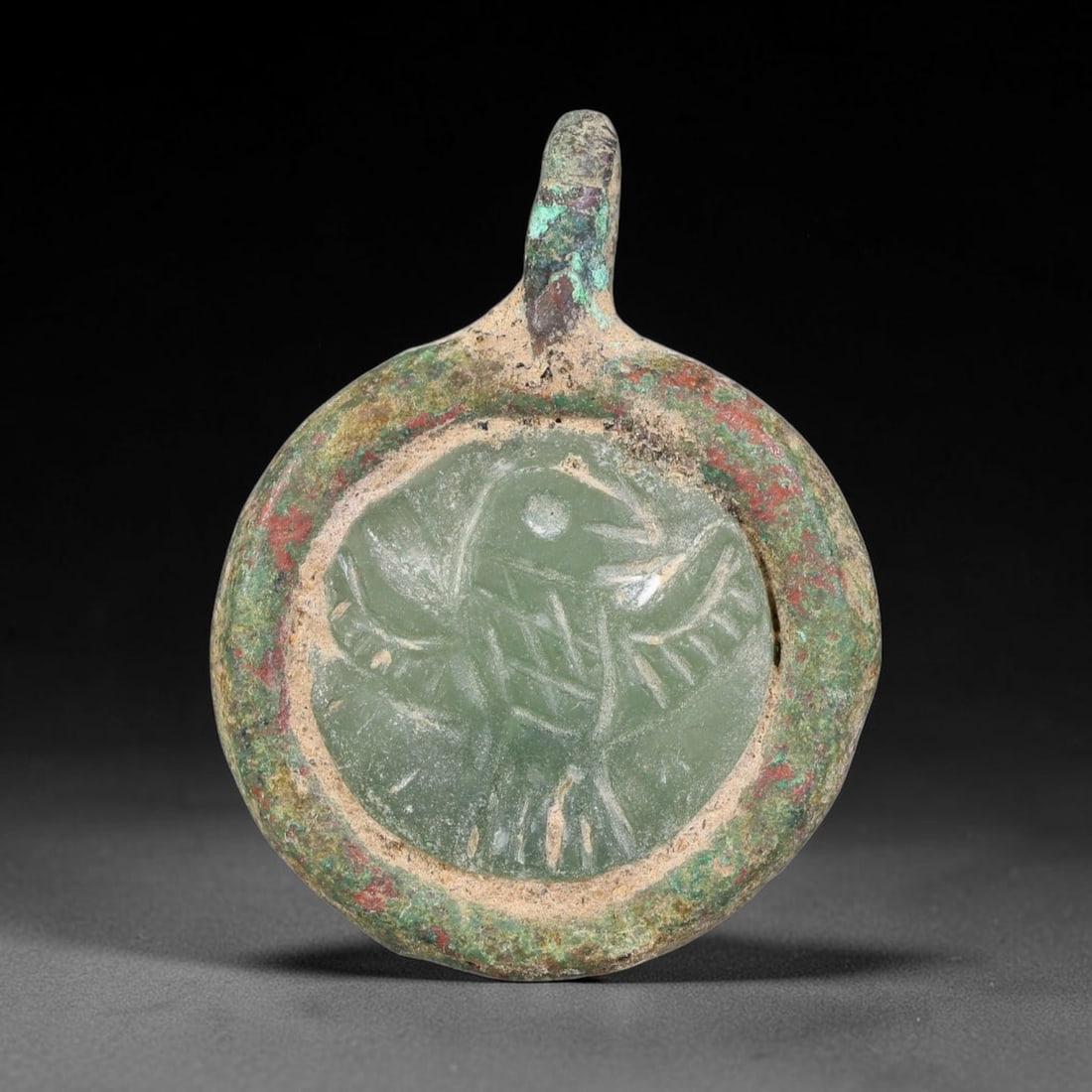 Ancient Medieval Byzantine Bronze Pendant With Stone Cameo (500-1200 CE), 44EH: This antique circular bronze pendant originates from medieval Byzantine cultural tradition, set with an inset carved stone cameo and made to serve as a wearable protective personal amulet. The bronze 