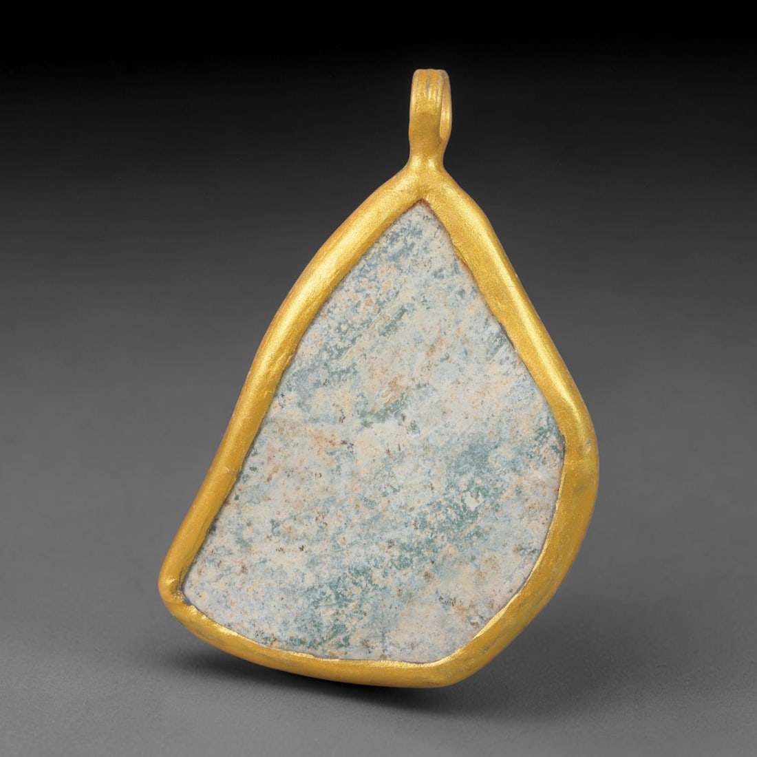 Ancient Roman Glass Slag in Modern Gilt-Edge Pendant, 31EH: This contemporary pendant is crafted from ancient Roman glass slag, featuring a fragmented, iridescent glass surface with weathered patina. The irregular form is bordered by a subtle gilt frame, added