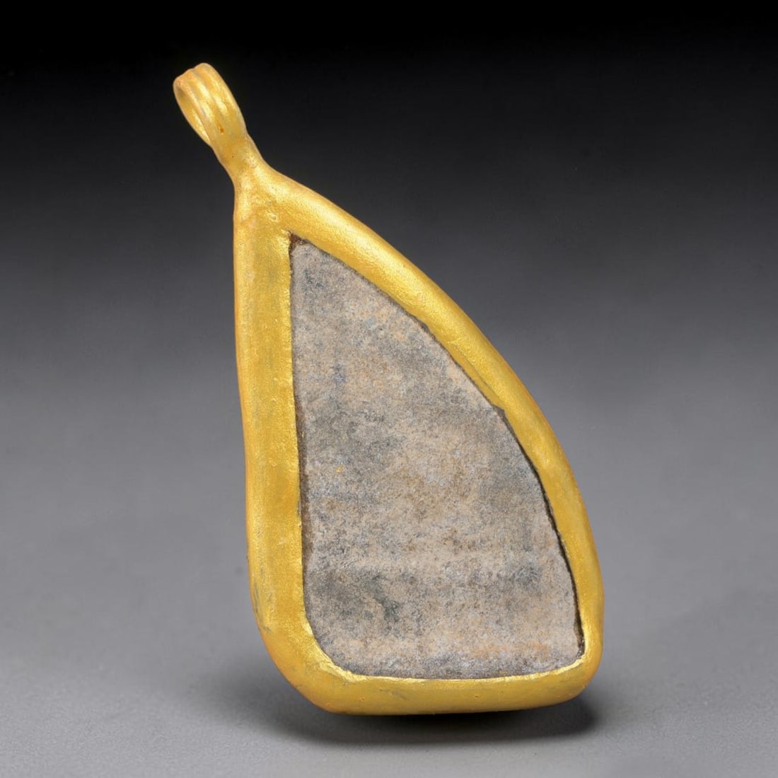 Ancient Roman Glass Slag in Modern Gilt-Edge Pendant, 29EH: This contemporary pendant is crafted from ancient Roman glass slag, featuring a fragmented, iridescent glass surface with weathered patina. The irregular form is bordered by a subtle gilt frame, added