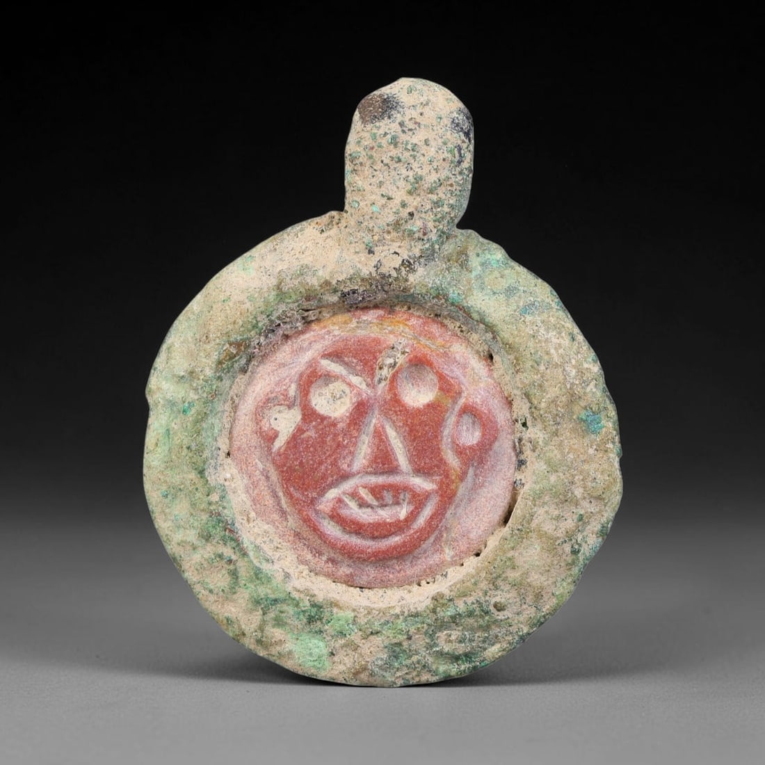 Ancient Medieval Byzantine Bronze Pendant With Stone Cameo (500-1200 CE), 72EH: This antique circular bronze pendant originates from medieval Byzantine cultural tradition, set with an inset carved stone cameo and made to serve as a wearable protective personal amulet. The bronze 