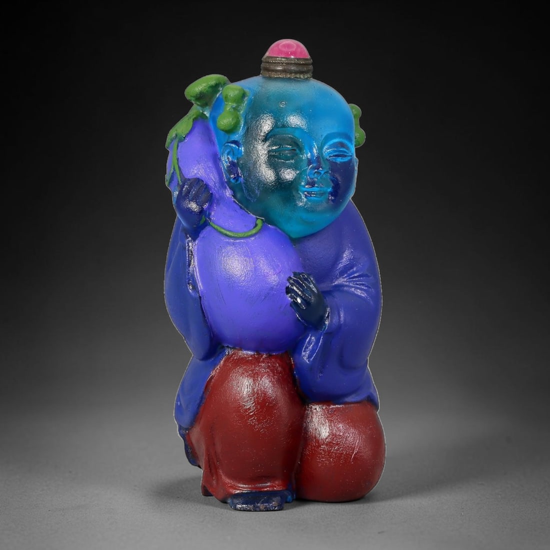 Vintage Chinese Liuli Glass Snuff Bottle - Boy Holding Purple Gourd, 39AS: This snuff bottle is moulded from translucent blue liuli glass for the head, modelled as a smiling boy kneeling while cradling a large painted purple gourd. His bright blue robe and red trousers are f