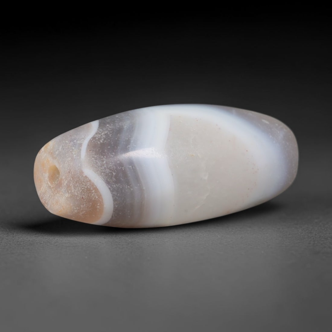 Ancient Indo-Scythian Curved White Banded Taupe Agate Barrel Bead (100 BCE - 200 CE), 79AD: This long flowing banded agate barrel bead originates from the Indo-Scythian steppe kingdoms of Central and South Asia, nomadic cultures that mastered agate carving to create protective talisman beads