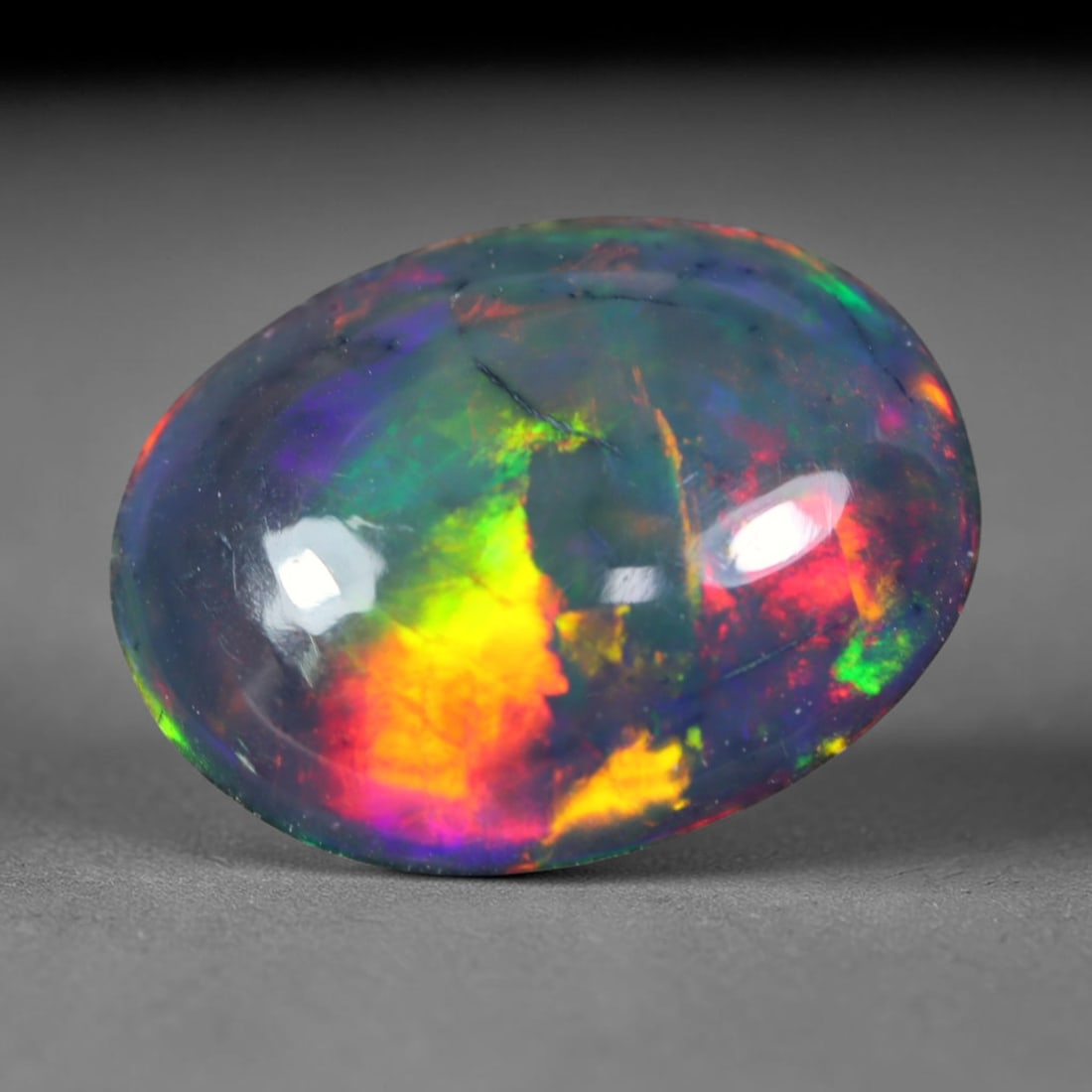 1.32ct Natural Ethiopian Welo Black Smoked Opal Cabochon Loose Gemstone, 9FL: This fully polished Ethiopian Welo opal features a dark smoked base with vivid, sweeping play-of-color shifting across its glossy dome surface, measured at 11x8.9x3mm. The black smoke treatment deepen