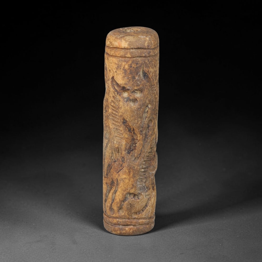 Ancient Mesopotamian Stone Cylinder Seal (c.2300-539 BCE), 66EF: This carved pale weathered stone cylinder seal originates from Ancient Mesopotamia. The cylindrical body features continuous incised imagery encircling the surface, framed by simple horizontal border 