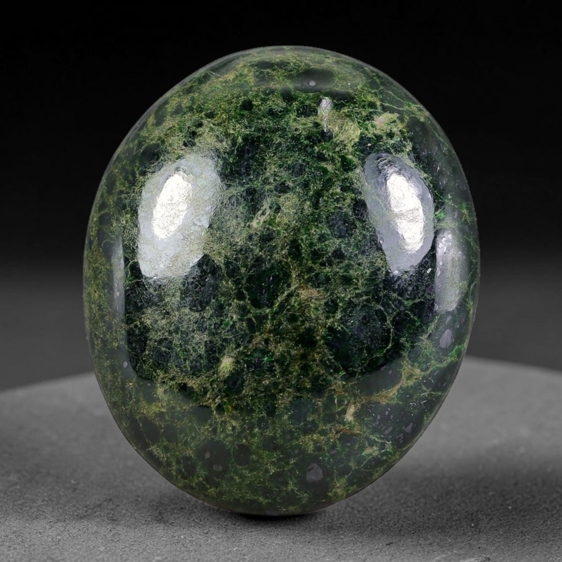 44ct Natural Burmese Type A Dark Green Net Vein Jadeite Jade Cabochon, 20FA: This single untreated natural Burmese Type A oval jadeite jade cabochon weighs 44ct with dimensions of 28.4x23.7x6.8mm. The deep forest green matrix is filled with dense mesh-shaped yellowish-brown ve