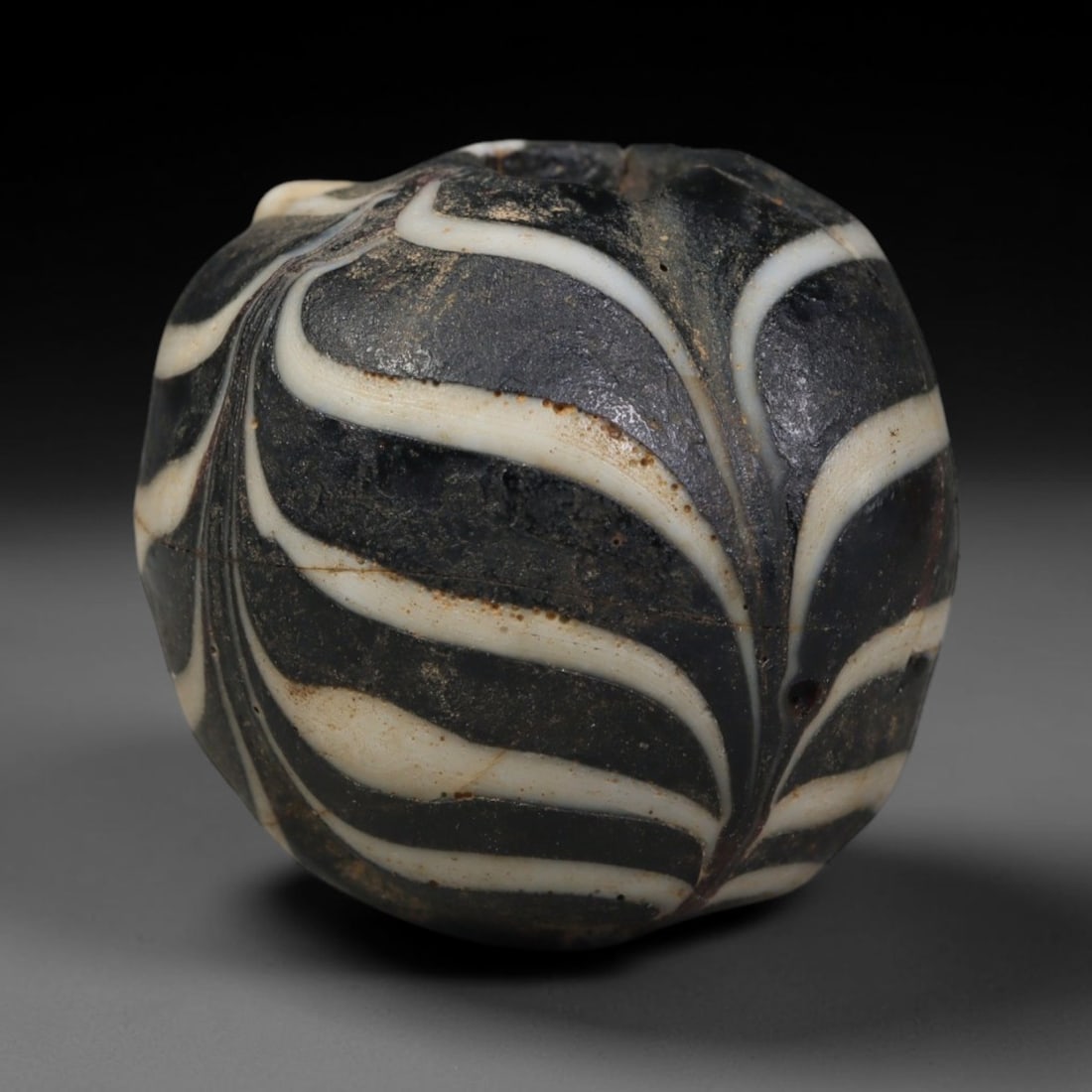 Ancient Islamic Hand Crafted Glass Bead Talisman, 24AC: Miniature antique wearable bead formed from hand-worked glass material, originating from ancient Islamic period glassmaking traditions across the Near East and North African cultural spheres. Glass wa