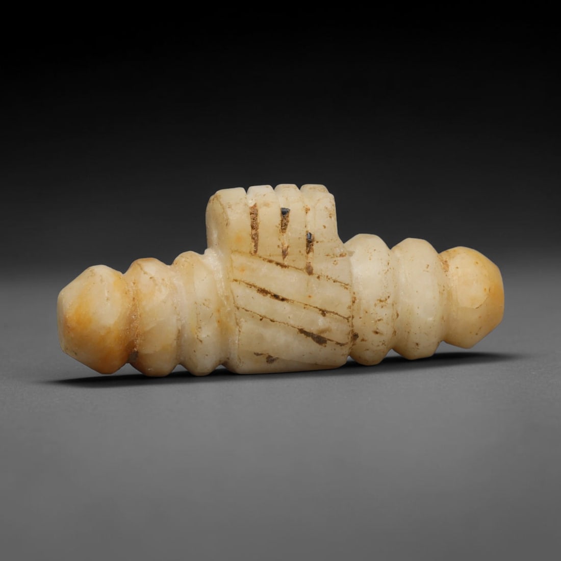 Ancient Mesopotamian Pale Stone Ritual Talisman (Early Dynastic Period), 37ED: This antique pale stone ritual talisman originates from Ancient Mesopotamia. The elongated artifact features symmetrical segmented terminals and a central rectangular panel decorated with incised line