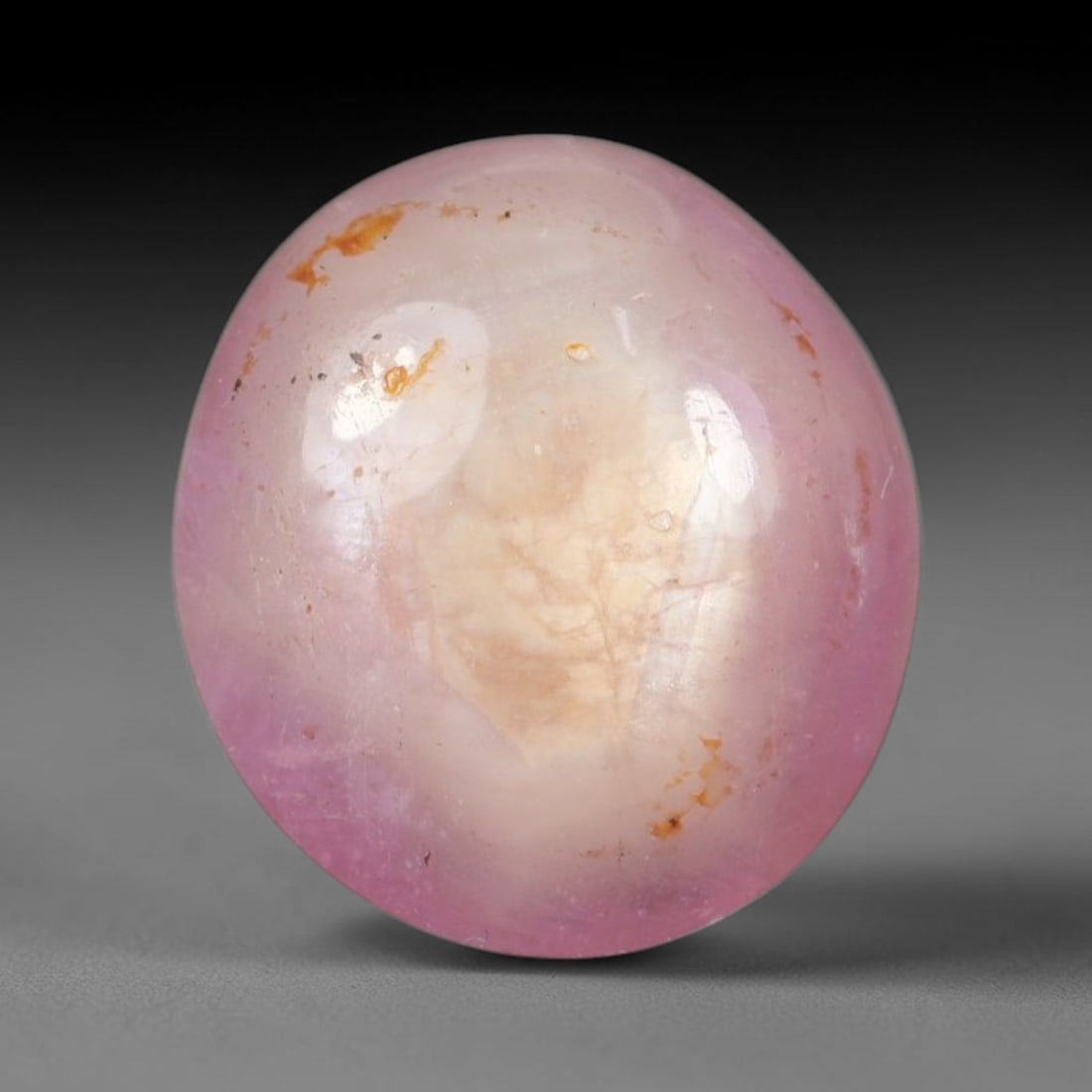 6.19ct Natural Mozambican Soft Bubblegum Pink Ruby Cabochon Loose Gemstone, 98AR: This smoothly polished domed ruby cabochon displays a gentle soft bubblegum pink body tone with faint natural linear mineral veining and tiny scattered rust-hued mineral flecks embedded within its tra