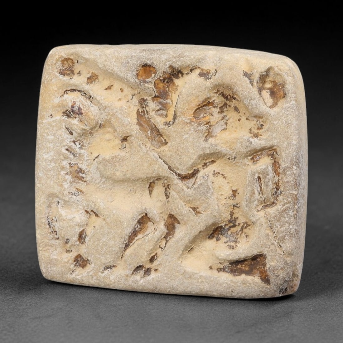 Ancient Neo-Hittite Square Limestone Stamp Seal (1200-800 BCE), 37EF: This square stamp seal is carved from pale limestone, originating from Iron Age Neo-Hittite cultures of Northern Syria and Eastern Anatolia. The seal face bears an intaglio depiction of a mounted figu