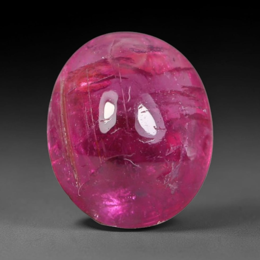 1.36ct Natural Brazilian Rubellite Tourmaline Cabochon Loose Gemstone, 19BC: This smoothly polished cabochon rubellite tourmaline features layered saturated pink-red body saturation with dense natural crystalline mineral flecks and fine internal fracture markings concentrated 