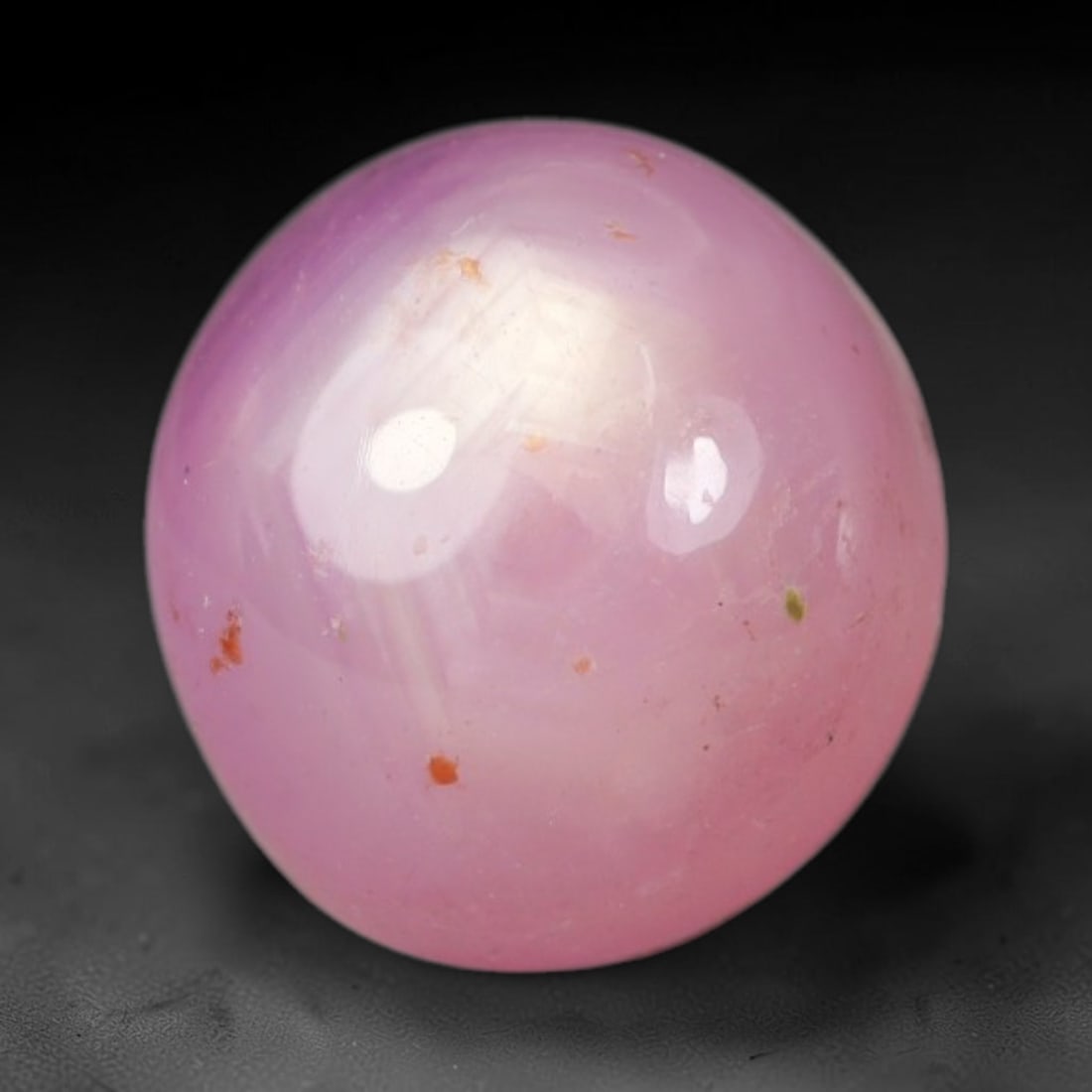 4.16ct Natural Mozambican Soft Bubblegum Pink Ruby Cabochon Loose Gemstone, 84AR: This smoothly polished domed ruby cabochon displays a gentle soft bubblegum pink body tone with faint natural linear mineral veining and tiny scattered rust-hued mineral flecks embedded within its tra