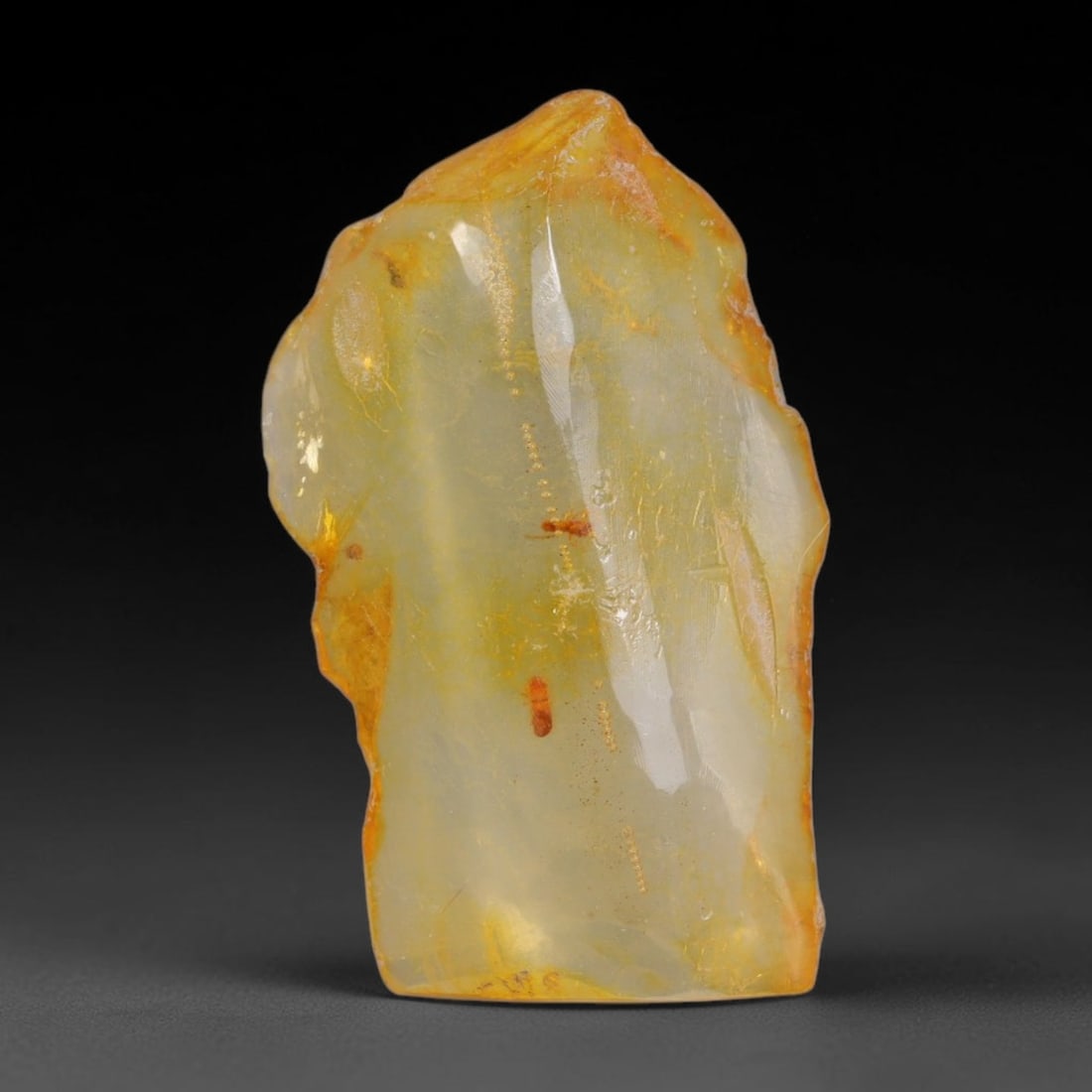 14.17ct Natural Baltic Polished Loose Freeform Amber Gemstone, 30AT: This smoothly polished freeform amber piece carries warm translucent organic clarity with fine natural fossil flecks and tiny mineral inclusions suspended throughout its 34x20mm flowing unstructured s