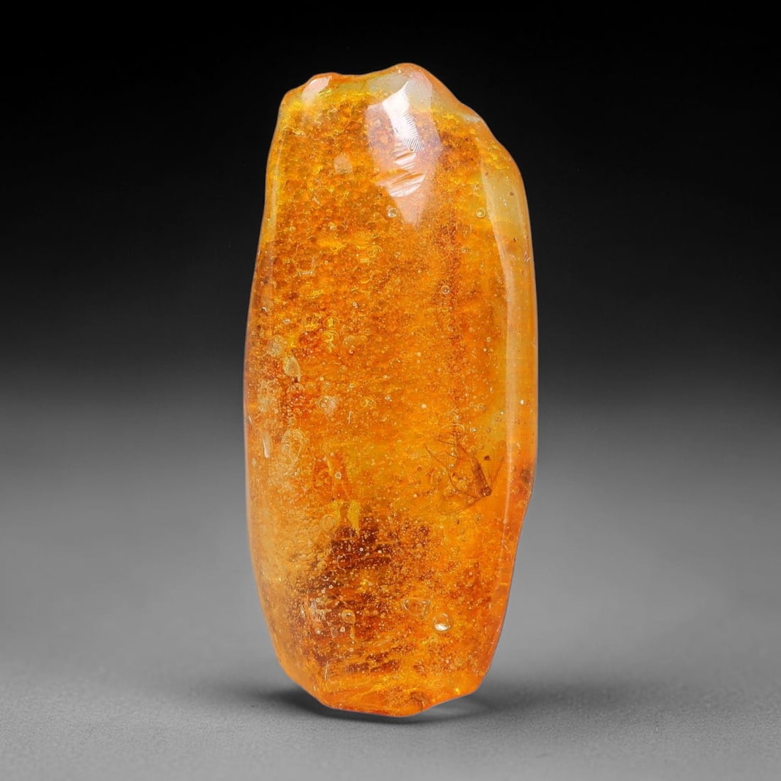 14.16ct Natural Baltic Polished Loose Freeform Amber Rough, 22EK: This smoothly polished freeform amber piece carries warm translucent organic clarity with fine natural fossil flecks and tiny mineral inclusions suspended throughout its 34x15x13mm flowing unstructure