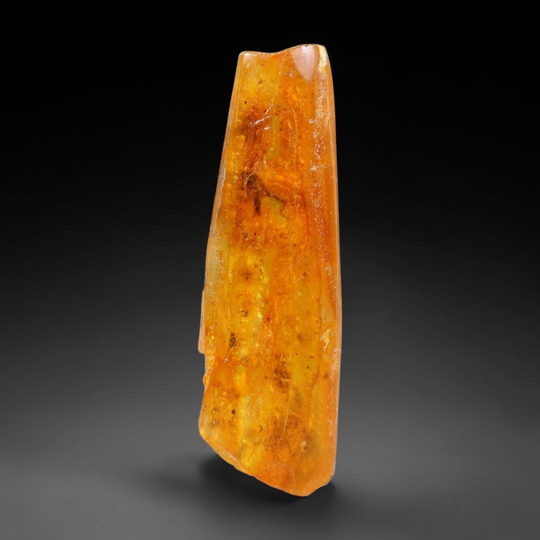 13.38ct Natural Baltic Polished Loose Freeform Amber Rough, 21EK: This smoothly polished freeform amber piece carries warm translucent organic clarity with fine natural fossil flecks and tiny mineral inclusions suspended throughout its 42x13x10mm flowing unstructure