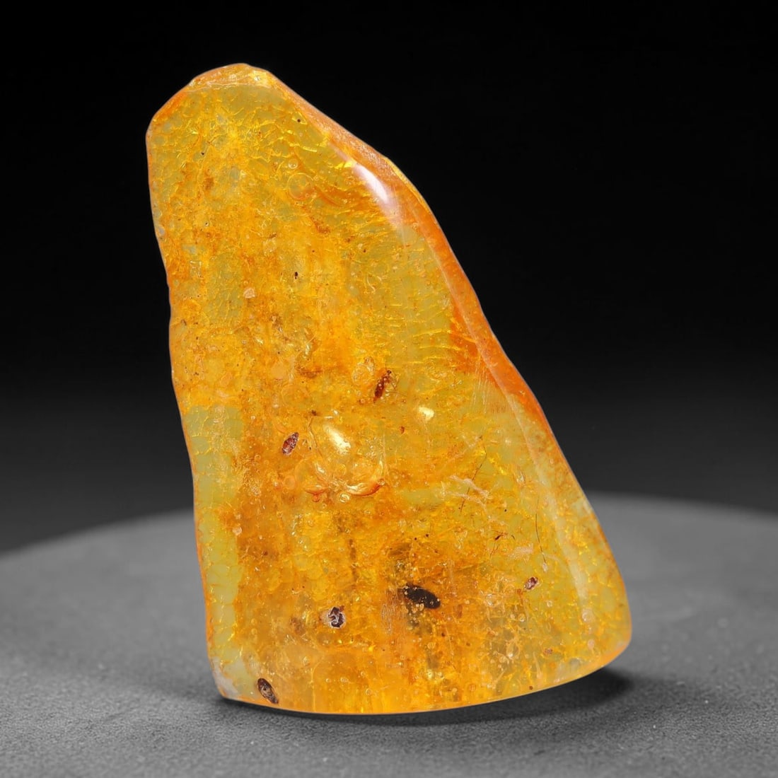 13.66ct Natural Baltic Polished Loose Freeform Amber Rough, 16EK: This smoothly polished freeform amber piece carries warm translucent organic clarity with fine natural fossil flecks and tiny mineral inclusions suspended throughout its 36x23x7mm flowing unstructured