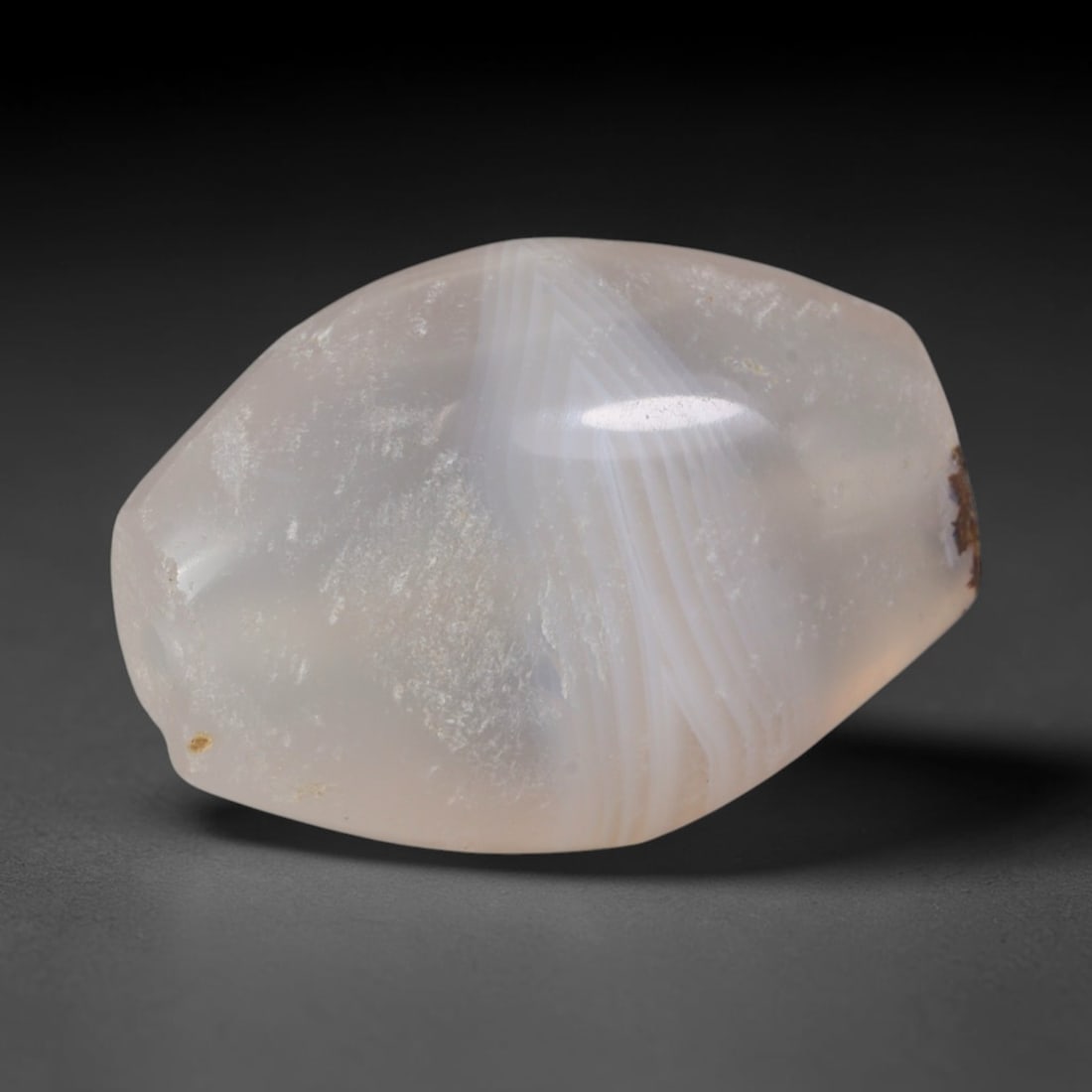 Ancient Greco-Bactrian Radiating Fan Banded Pale Peach Agate Barrel Bead (256-130 BCE), 4AE: This substantial translucent banded agate barrel bead originates from the Greco-Bactrian Kingdom, a Hellenistic Central Asian civilization that fused Greek and steppe lapidary traditions to craft tali