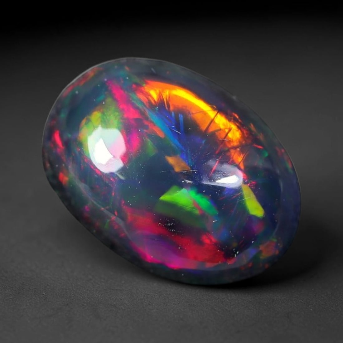 2.04ct Natural Ethiopian Welo Black Smoked Opal Cabochon Loose Gemstone, 10FX: This fully polished Ethiopian Welo opal features a dark smoked base with vivid, sweeping play-of-color shifting across its glossy dome surface, measured at 11x8x4mm. The black smoke treatment deepens 