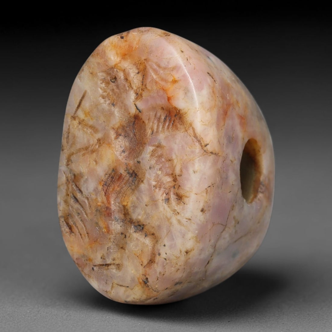 Ancient Medieval Early Islamic Period Pink Veined Stone Conoid Stamp Seal (c.7th-11th Century CE),: This pierced conoid stamp seal is carved from naturally veined pink stone, featuring an incised figural scene. Visible age cracks, mineral staining and smooth wear from extensive ancient handling. The