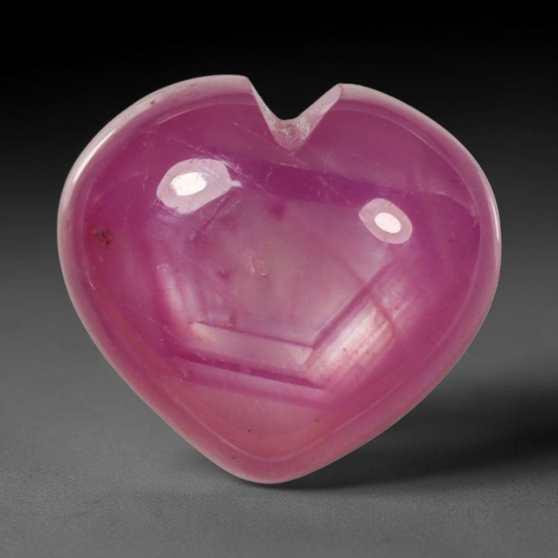 7.15ct Natural Mozambique Hot Pink Ruby Loose Gemstone, 63BP: This heart shaped Mozambique ruby cabochon measures 10.8x10x5.6mm, showcasing a vivid saturated hot pink body paired with stunning natural hexagonal crystal growth banding that forms a distinct geomet