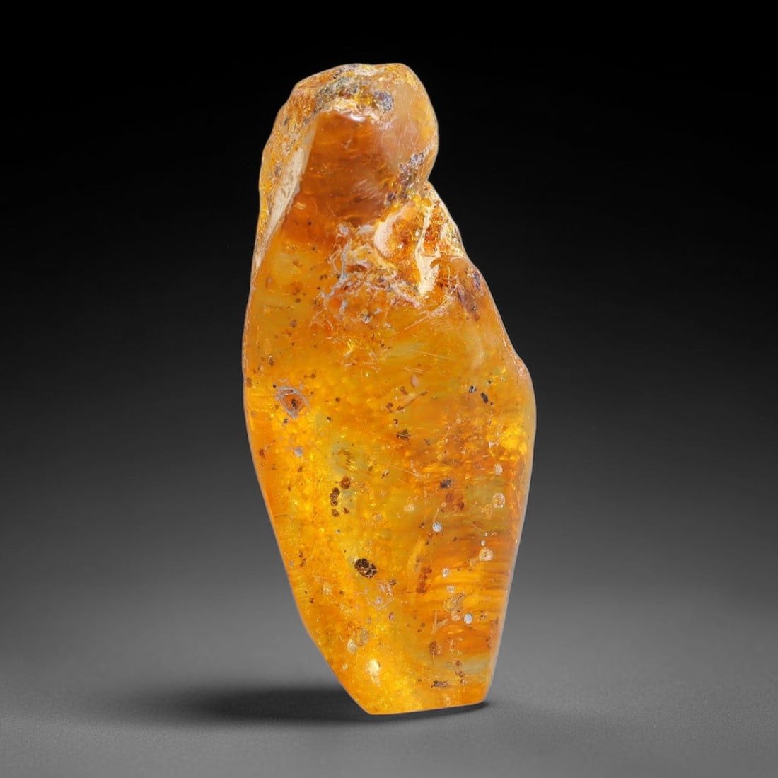 15.44ct Natural Baltic Polished Loose Freeform Amber Gemstone, 87FL: This smoothly polished freeform amber piece carries warm translucent organic clarity with fine natural fossil flecks and tiny mineral inclusions suspended throughout its 35x13x10mm flowing unstructure