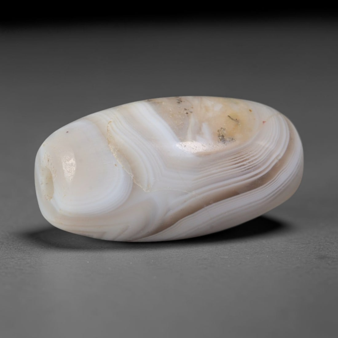 Ancient Six Dynasties Wavy Cream Banded Agate Barrel Bead (220-589 CE), 89AD: This antique flowing banded agate barrel bead originates from China's Six Dynasties Period, a culturally diverse era where stone adornment blended local Chinese craft with Central Asian Silk Road orna