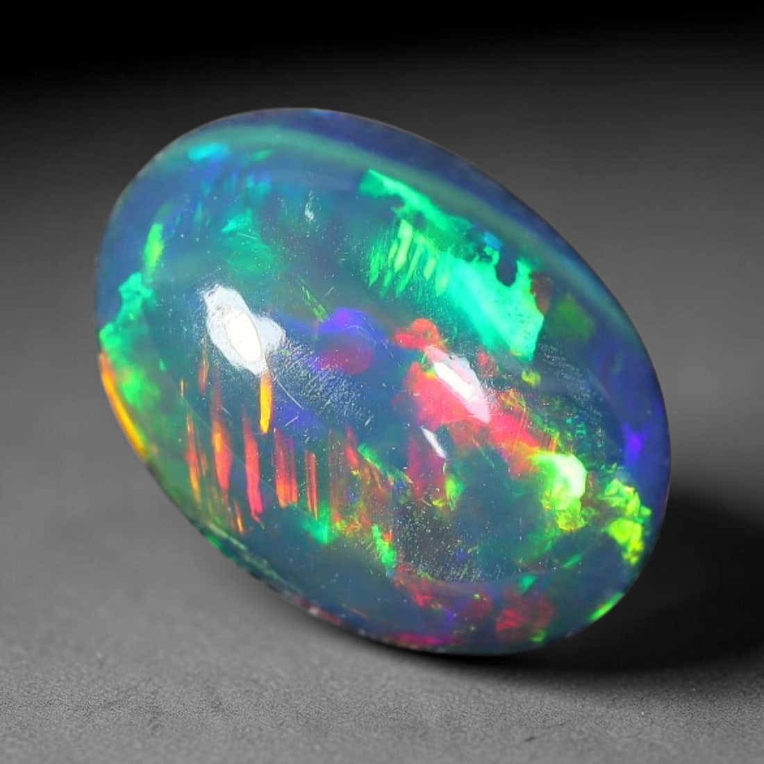 1.56ct Natural Ethiopian Welo Black Smoked Opal Cabochon Loose Gemstone, 70FX: This fully polished Ethiopian Welo opal features a dark smoked base with vivid, sweeping play-of-color shifting across its glossy dome surface, measured at 10x7x4mm. The black smoke treatment deepens 