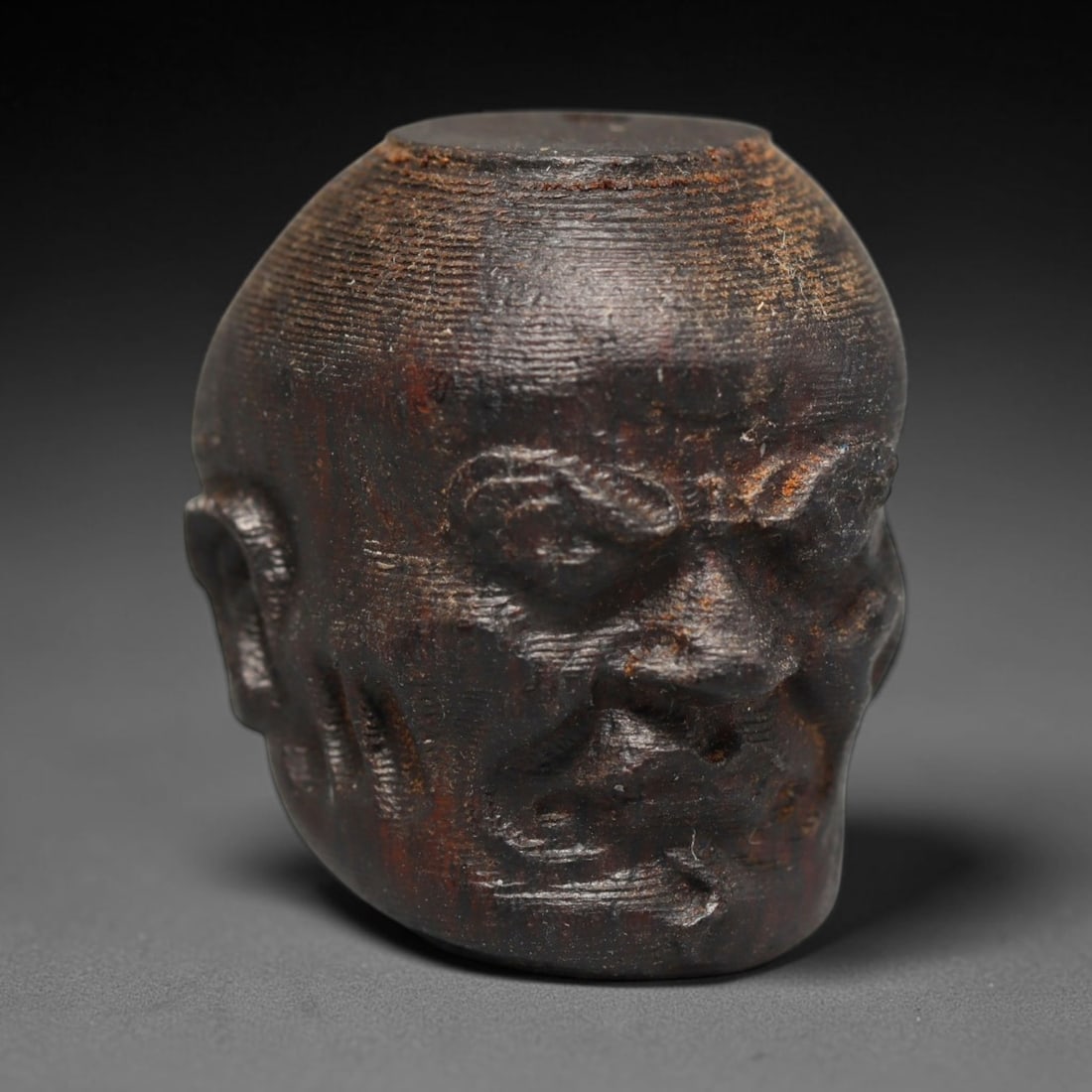A Chinese Agar Wood Carved Head Art Bead, 30BX: Chinese agar wood head-form art bead measuring 22 x 20 mm. Detailed sculpted facial features cover the exterior surface, with a continuous central bore designed for stringing within beaded strands. Th