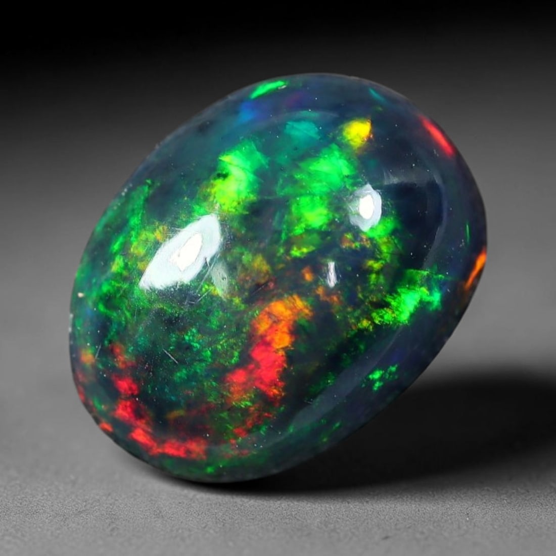 2.15ct Natural Ethiopian Welo Black Smoked Opal Cabochon Loose Gemstone, 66FX: This fully polished Ethiopian Welo opal features a dark smoked base with vivid, sweeping play-of-color shifting across its glossy dome surface, measured at 10x8x5mm. The black smoke treatment deepens 