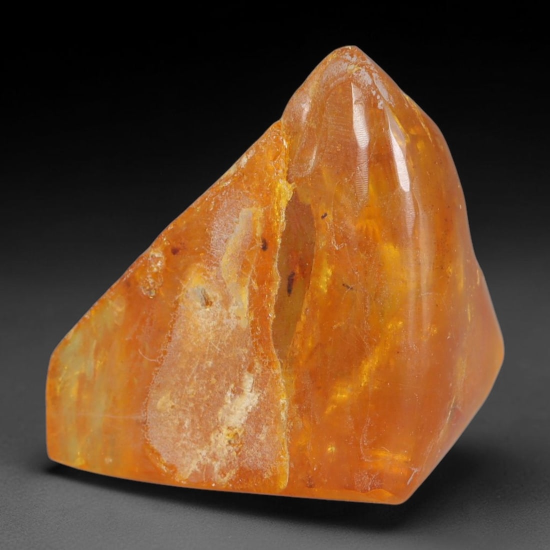 25.54ct Natural Baltic Polished Loose Freeform Amber Gemstone, 36AT: This smoothly polished freeform amber piece carries warm translucent organic clarity with fine natural fossil flecks and tiny mineral inclusions suspended throughout its 24x23mm flowing unstructured s