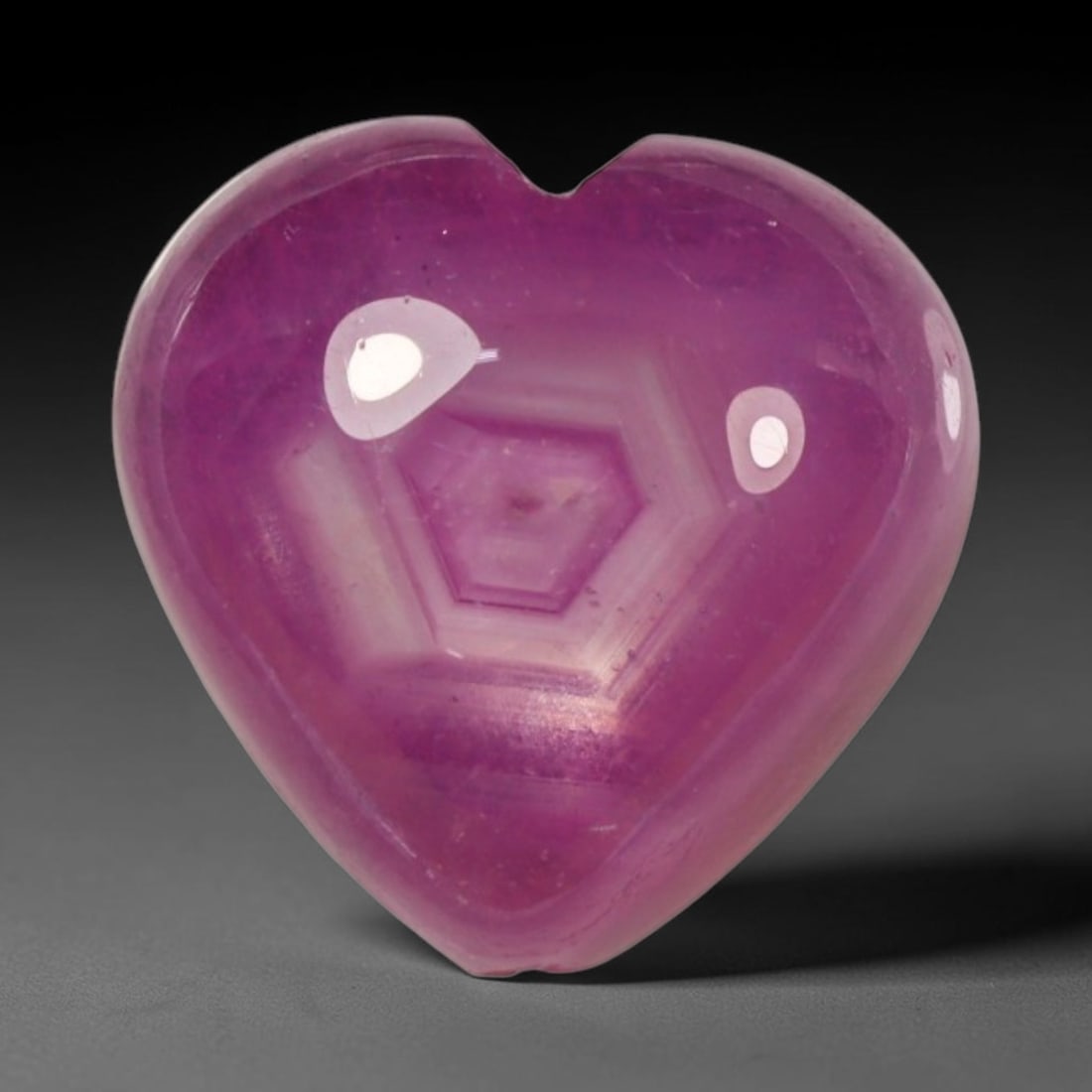 8.67ct Natural Mozambique Hot Pink Ruby Loose Gemstone, 66BP: This heart shaped Mozambique ruby cabochon measures 10.4x10.1x7mm, showcasing a vivid saturated hot pink body paired with stunning natural hexagonal crystal growth banding that forms a distinct geomet