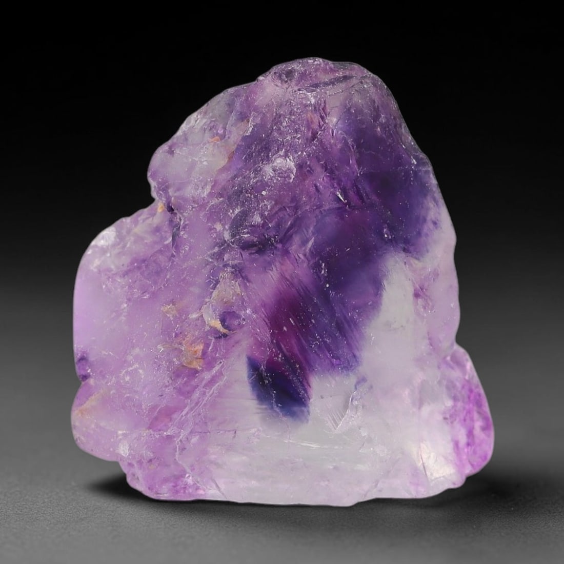 115ct Natural Chinese Deep Violet Purple Fluorite Rough, 84AT: This rugged fluorite rough boasts rich layered violet purple saturation blended with warm rust-colored mineral inclusions that streak its uneven raw surface, soft translucency lets light drift through