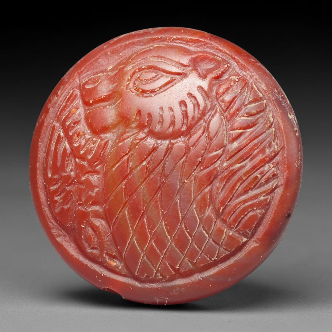 Ancient Medieval Early Islamic Period Carnelian Cameo Bead (c.7th-11th Century CE), 78EC: This circular pierced bead is carved from natural carnelian, bearing a detailed cameo relief of a feline creature, a prominent protective symbol in medieval Near Eastern talismanic glyptic art. Fine s