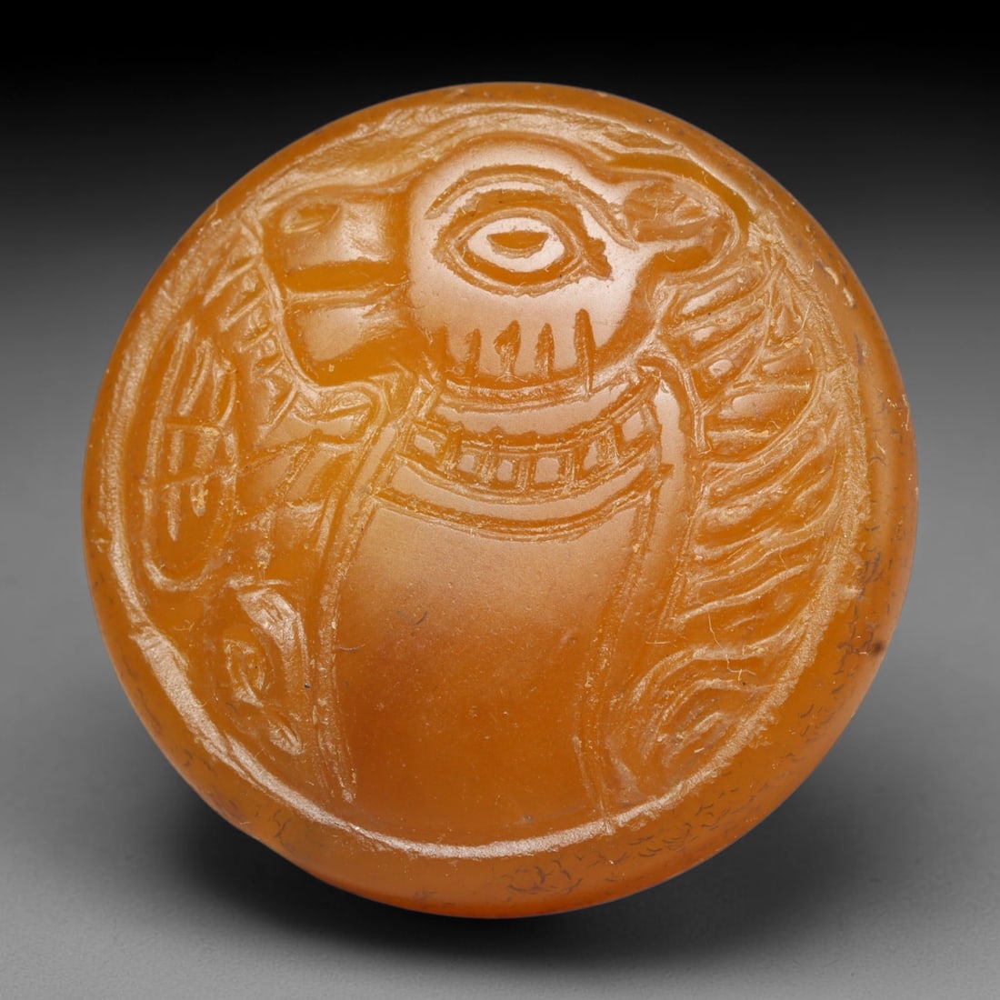 Ancient Medieval Early Islamic Period Carnelian Cameo Bead (c.7th-11th Century CE), 77EC: This circular pierced bead is carved from natural carnelian, bearing a detailed cameo relief of a feline creature, a prominent protective symbol in medieval Near Eastern talismanic glyptic art. Fine s
