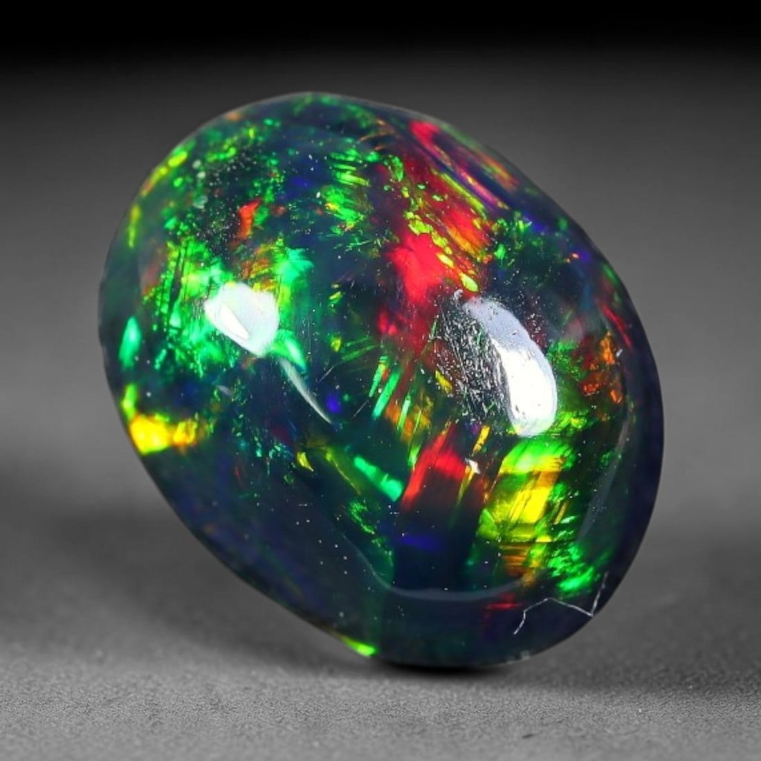 2.09ct Natural Ethiopian Welo Black Smoked Opal Cabochon Loose Gemstone, 50FX: This fully polished Ethiopian Welo opal features a dark smoked base with vivid, sweeping play-of-color shifting across its glossy dome surface, measured at 10x7x5mm. The black smoke treatment deepens 