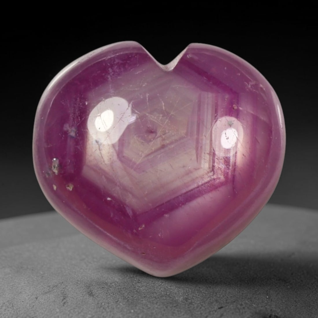 11.80ct Natural Mozambique Hot Pink Ruby Loose Gemstone, 67BP: This heart shaped Mozambique ruby cabochon measures 12.2x11.4x7mm, showcasing a vivid saturated hot pink body paired with stunning natural hexagonal crystal growth banding that forms a distinct geomet