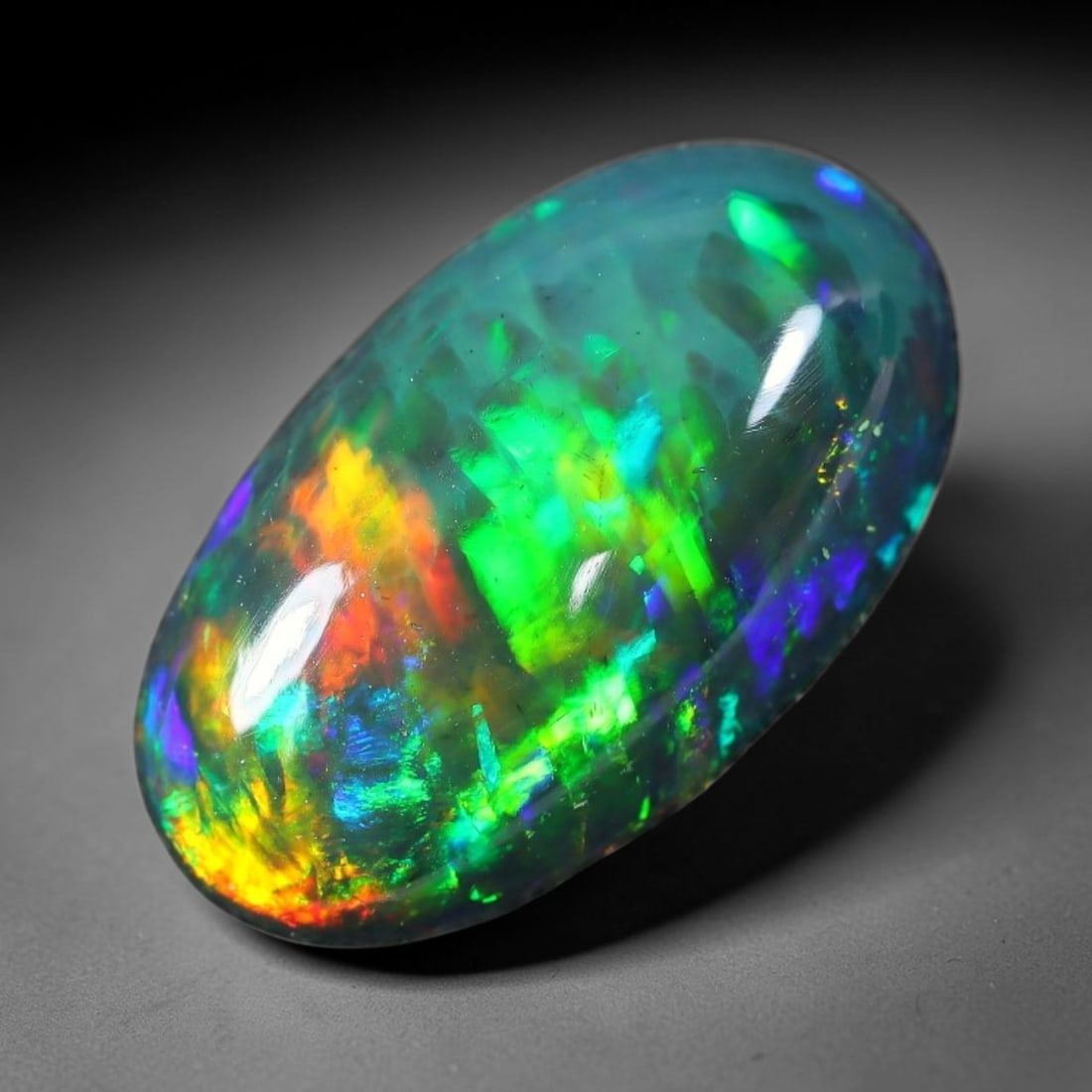 2.70ct Natural Ethiopian Welo Black Smoked Opal Cabochon Loose Gemstone, 33FX: This fully polished Ethiopian Welo opal features a dark smoked base with vivid, sweeping play-of-color shifting across its glossy dome surface, measured at 11x8x4mm. The black smoke treatment deepens 