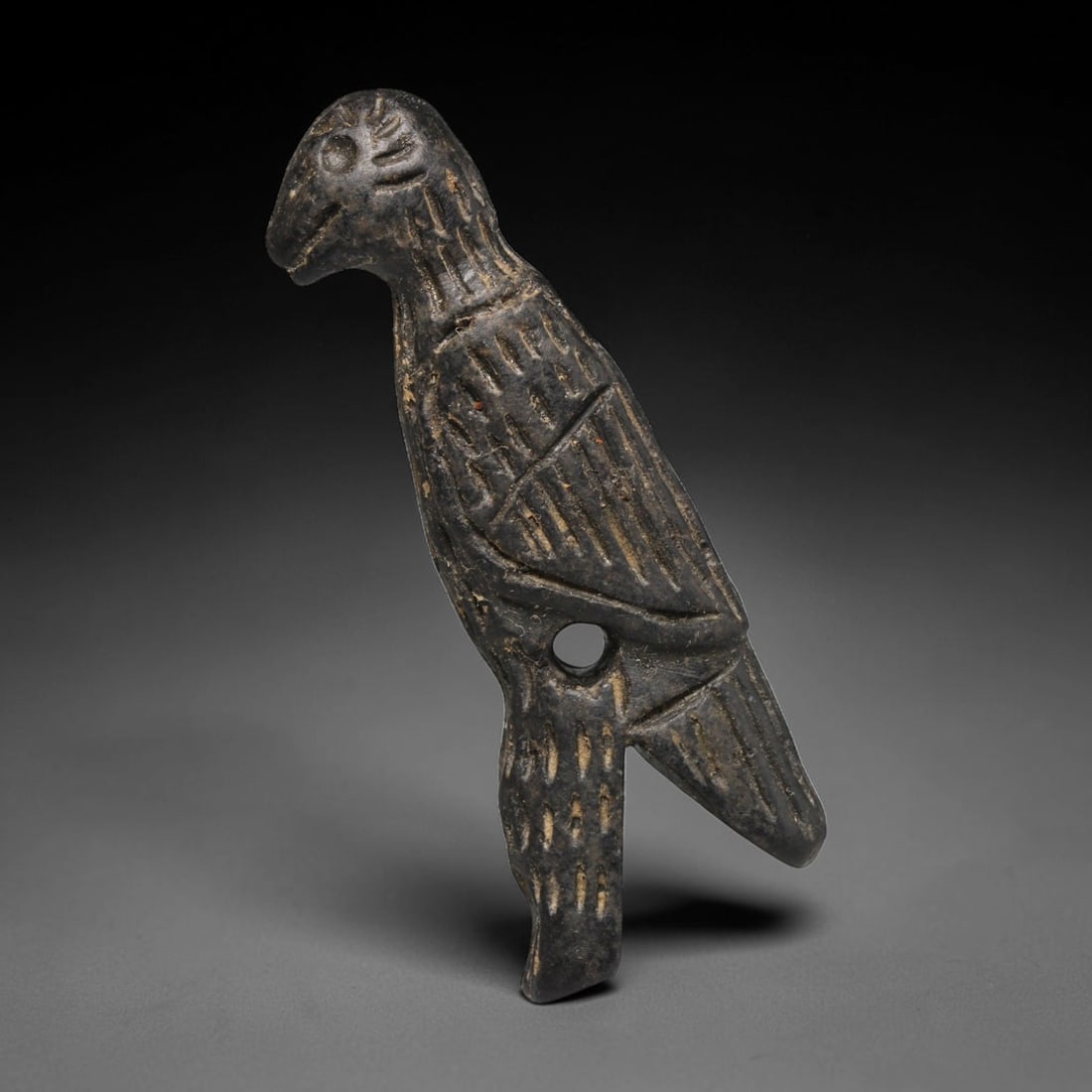 Ancient Sasanian Persian Dark Stone Avian Amulet (c.224-651 CE), 5ED: This carved dark stone avian amulet originates from the Sasanian Persian Empire (c.224-651 CE). Rendered in profile as a standing raptor, the talisman features precise incised linear detailing depicti