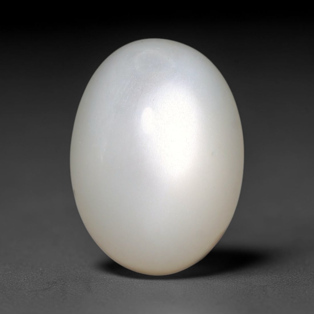 11.89ct Natural Ceylon White Moonstone Cabochon Loose Gemstone, 100FX: This natural Ceylon moonstone cabochon carries a milky white body showcasing classic adularescence. Fine mineral inclusions are visible within the gem. Dimensions measure 15x11x9mm, mined in Sri Lanka