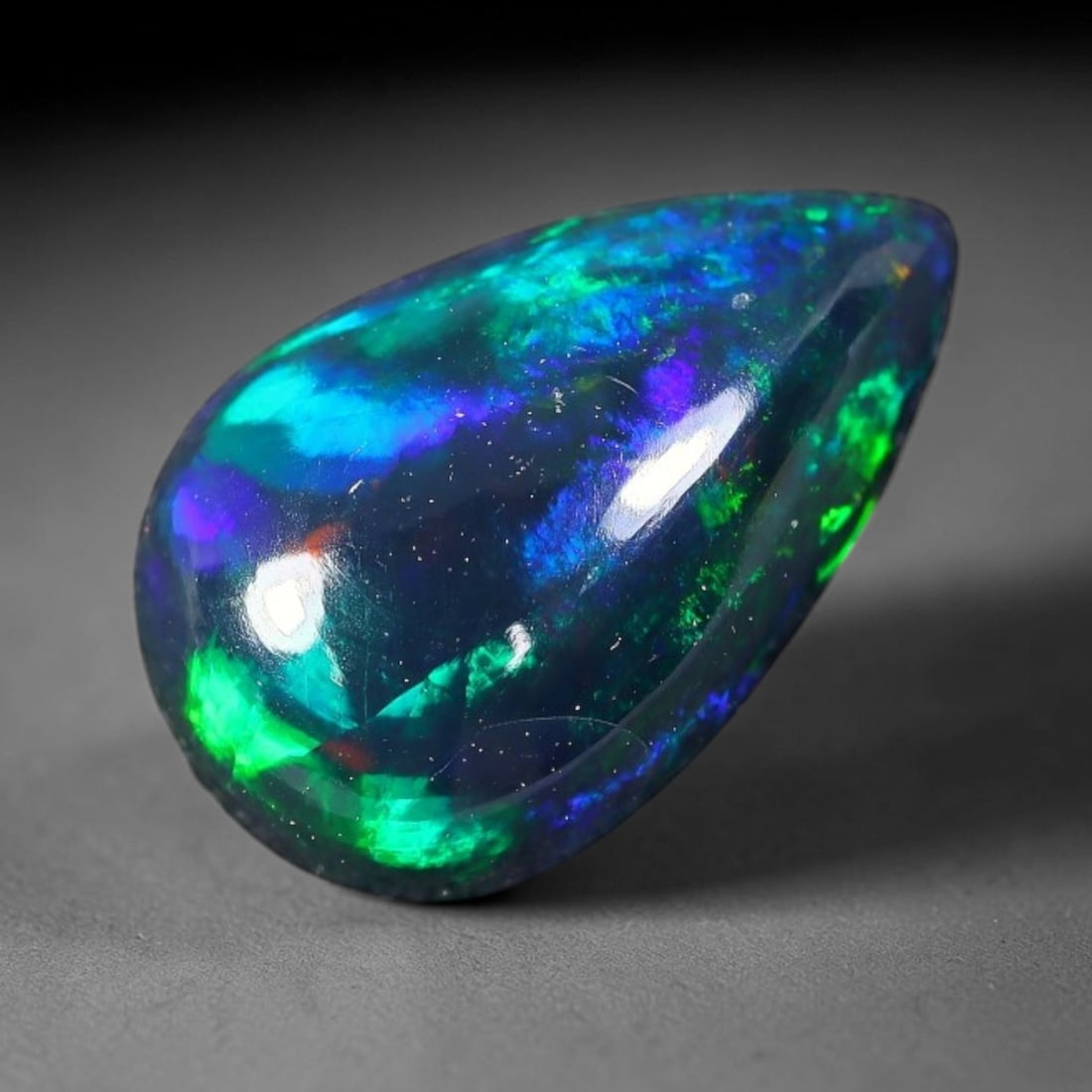 1.85ct Natural Ethiopian Welo Black Smoked Opal Cabochon Loose Gemstone, 80FX: This fully polished Ethiopian Welo opal features a dark smoked base with vivid, sweeping play-of-color shifting across its glossy dome surface, measured at 12x7x4mm. The black smoke treatment deepens 
