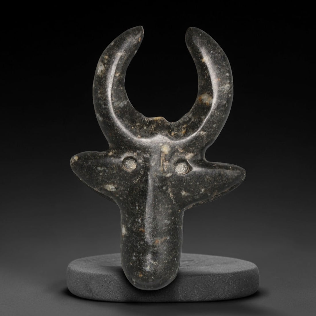Ancient Sasanian Persian Bull Head Stone Amulet (224-651 CE), 7ED: This antique dark speckled stone bull head amulet originates from the Sasanian Persian Empire, where bovine iconography represented strength and divine protection within Zoroastrian belief systems. Th