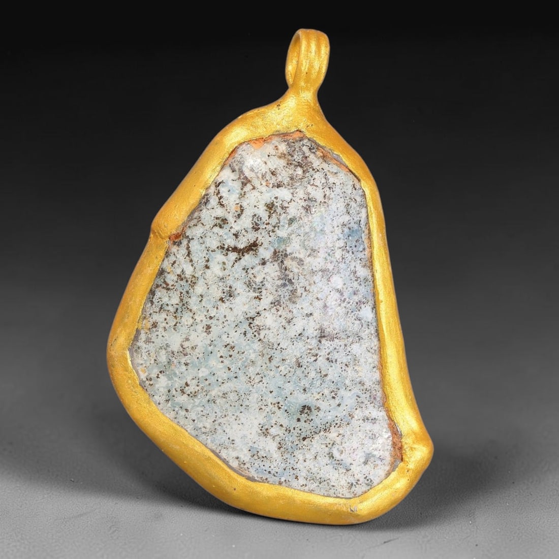 Ancient Roman Glass Slag in Modern Gilt-Edge Pendant, 57FY: This contemporary pendant is crafted from ancient Roman glass slag, featuring a fragmented, iridescent glass surface with weathered patina. The irregular form is bordered by a subtle gilt frame, added